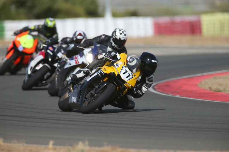 three motorcycle riders racing on the road during the day