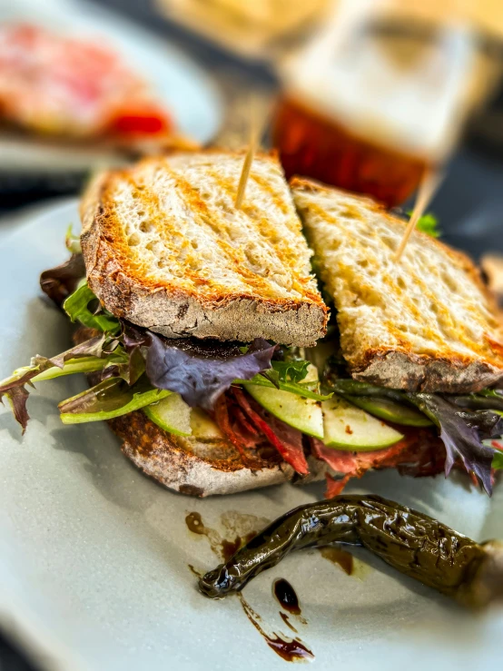 a big sandwich and some small peppers on the plate