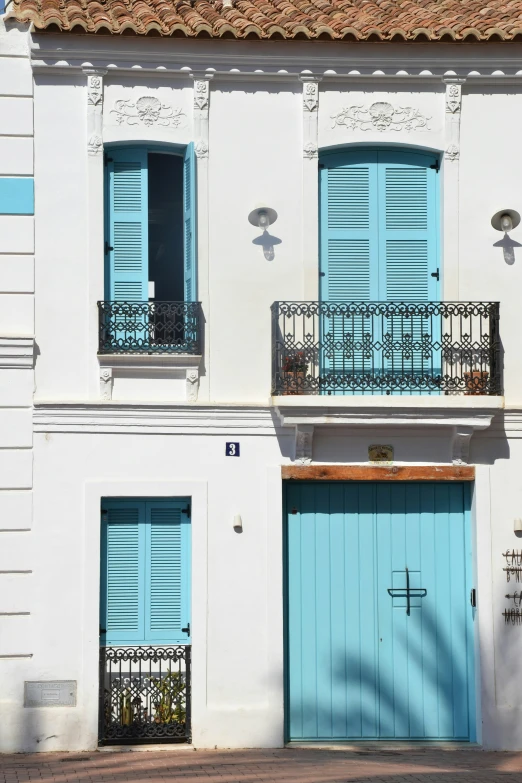 a white building with blue shutters and a balcony