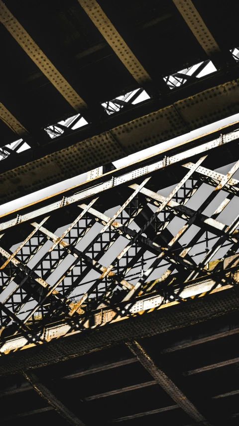 a train traveling under an overpass with metal tracks