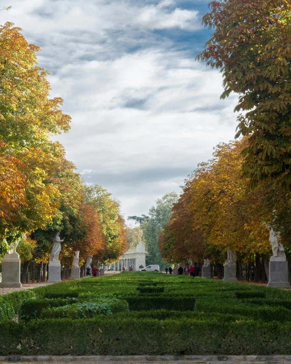 people walking in the autumn past a garden with various trees