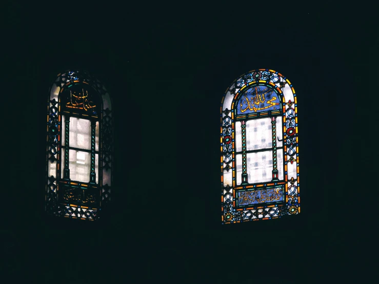 two different stained glass windows sitting in a dark room