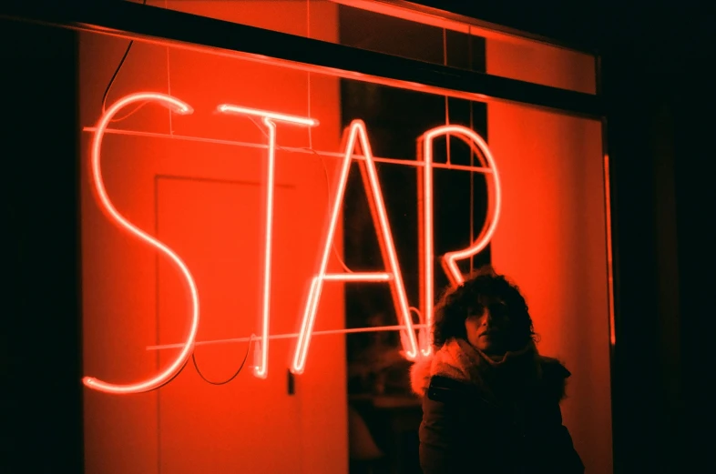 a person standing in front of a store with bright neon lights