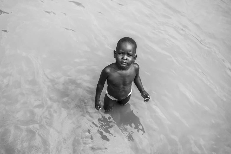 a black and white image of a boy playing in the water