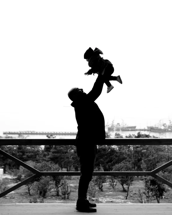 black and white image of man holding up baby girl