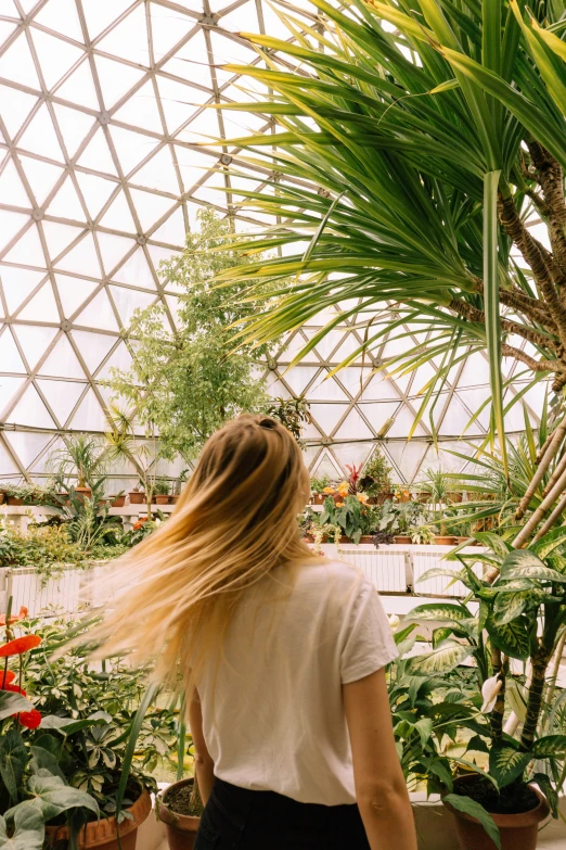 the woman is walking through the tropical house with long hair
