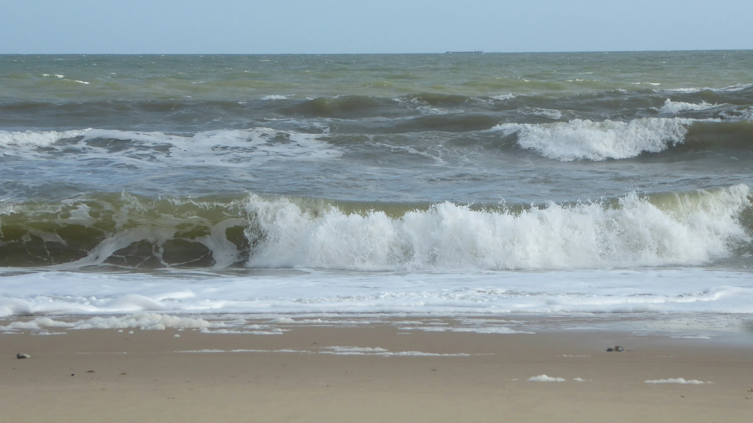 waves are crashing onto the beach as it rains