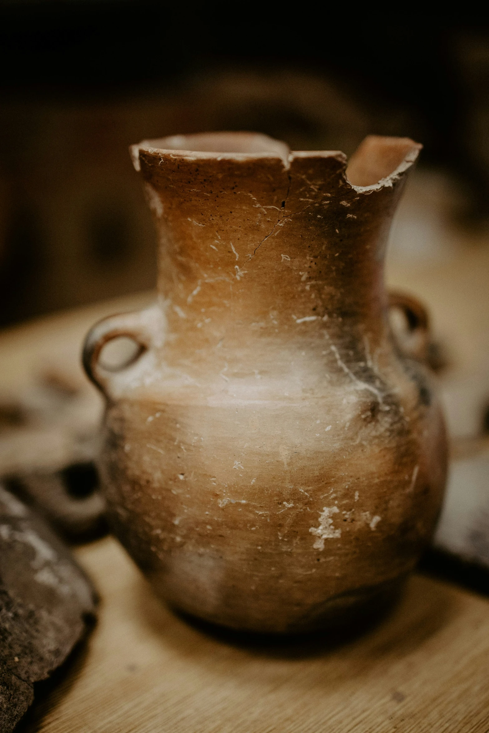 an ancient looking vase sitting on a wood surface