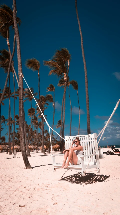 a woman sits on a white bench surrounded by trees and water