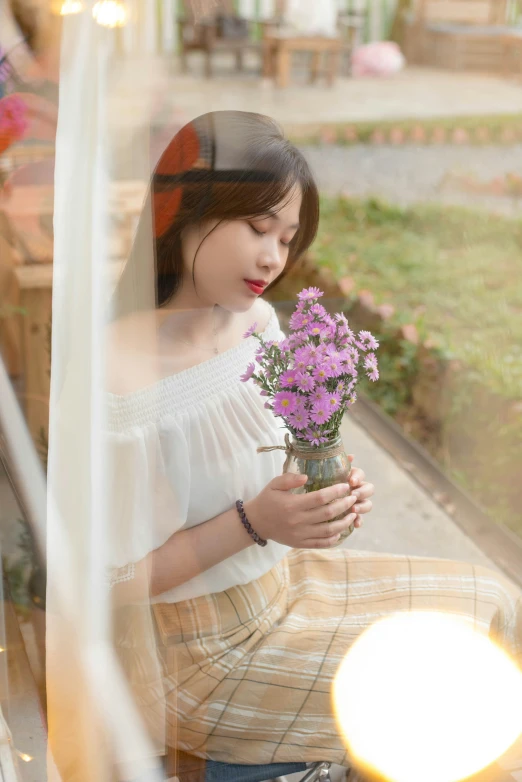 the woman is sitting down and smelling the flowers