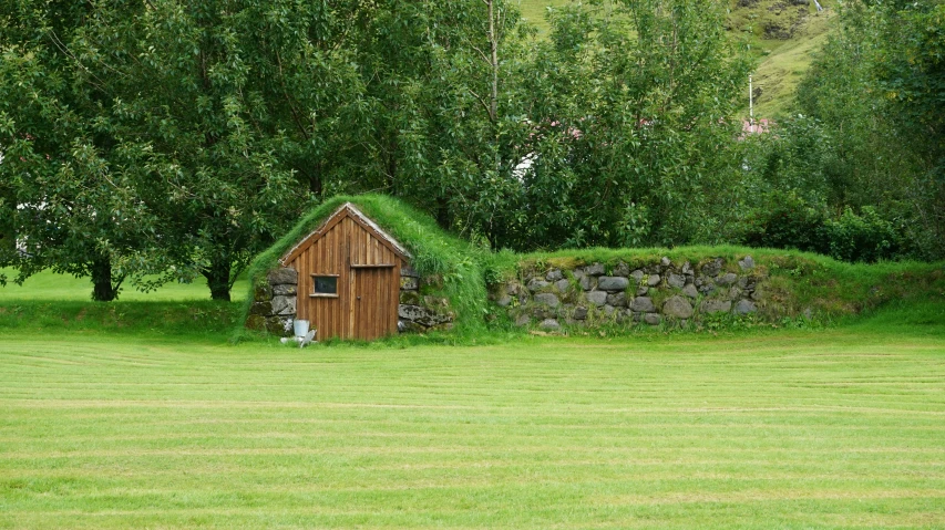 a small building sitting on the ground in front of some trees