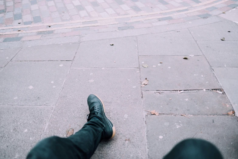 a persons foot is sitting on the sidewalk