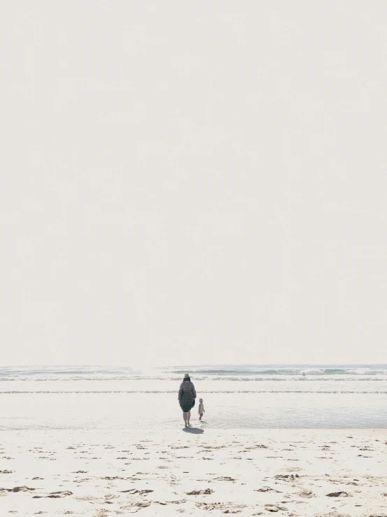 two people walking on the beach while carrying surfboards