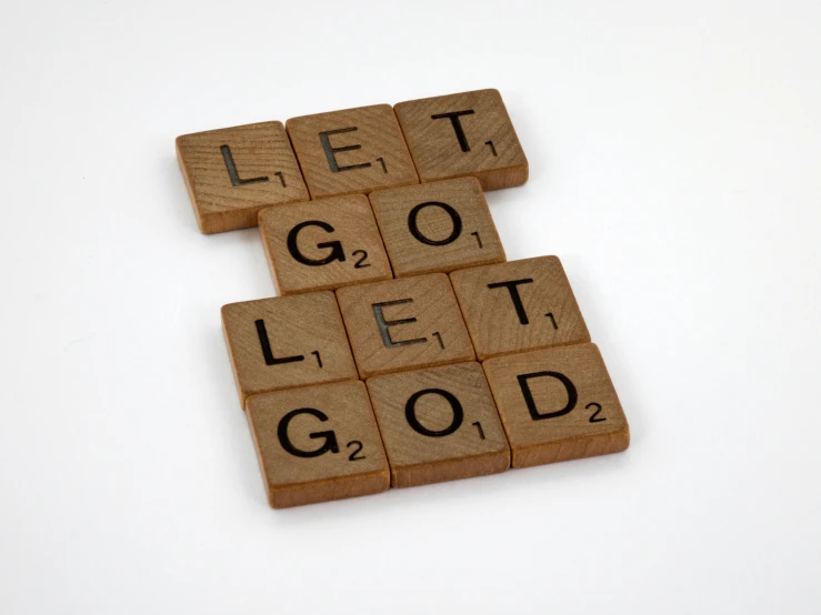 four scrabble tiles on a white background, that says let it go let it go