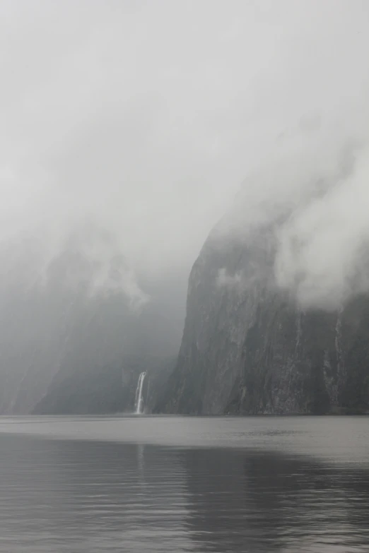 a boat in the water near mountains covered with mist