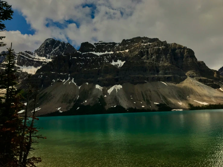 a mountain side is reflecting in the green water