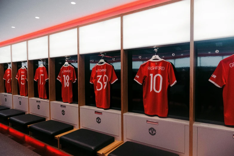 a long line of red soccer jerseys is hanging on the wall