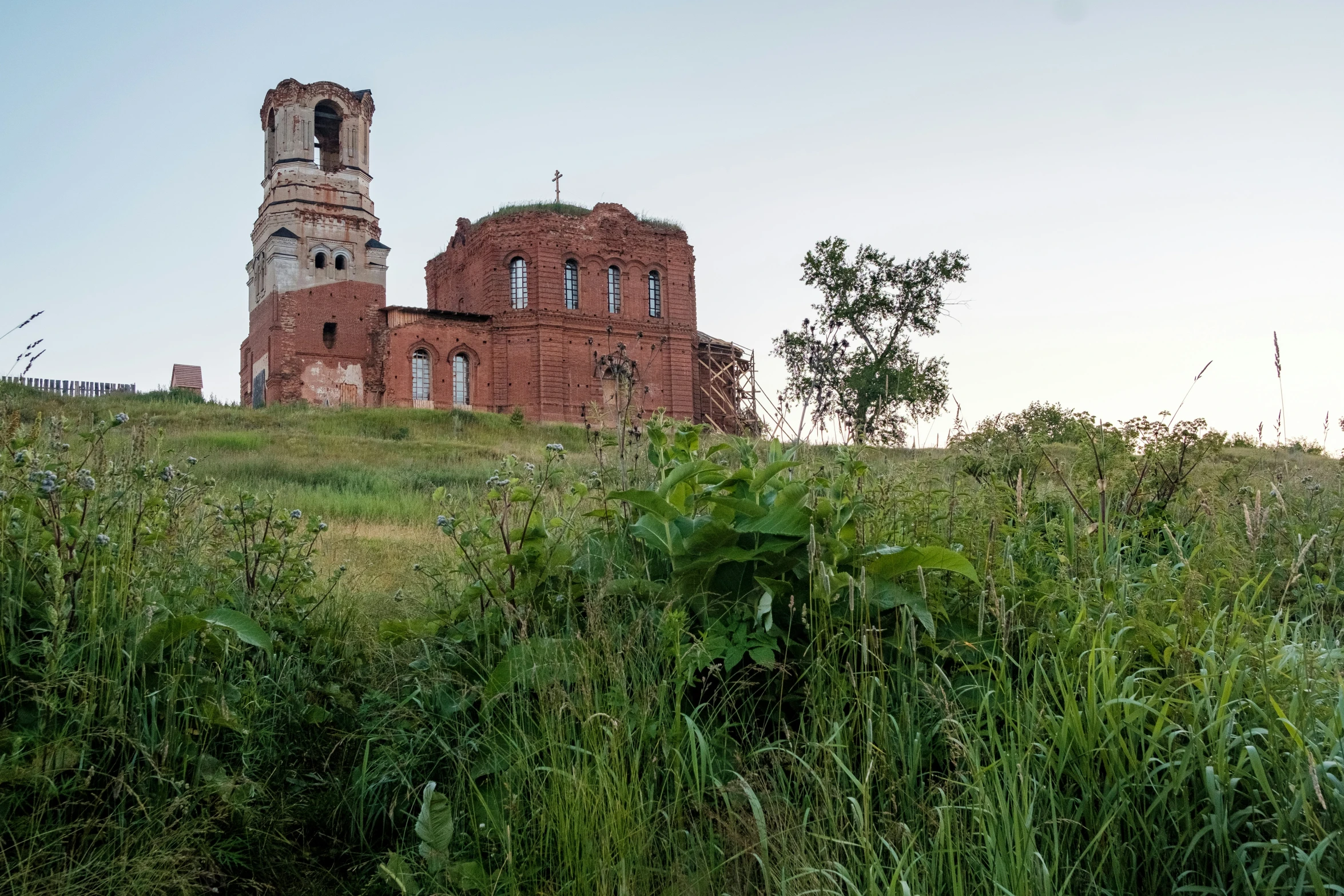 a very old building is sitting on the top of a grassy hill