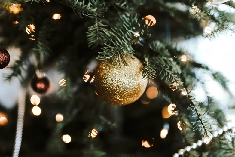 a golden ornament on a green christmas tree