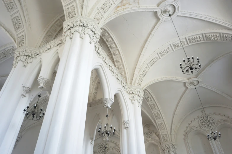 a ceiling with white columns, chandeliers and lights in the center