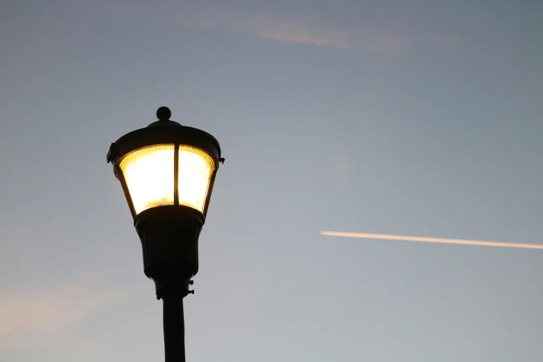 a street lamp with an airplane flying overhead