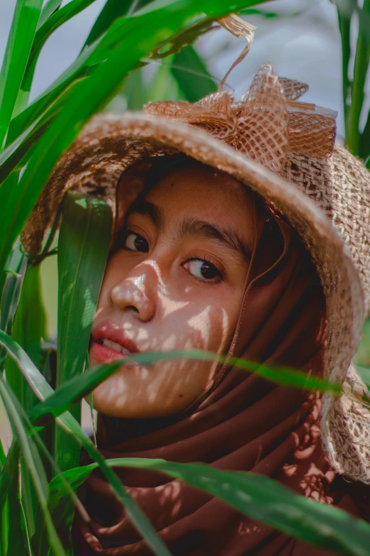 an asian woman with a hat, wearing a scarf and looking up