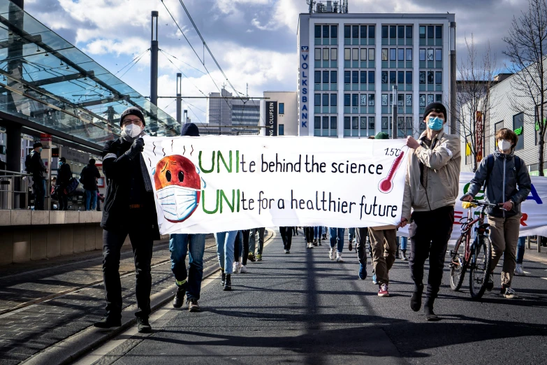 people walking with signs wearing masks in a street