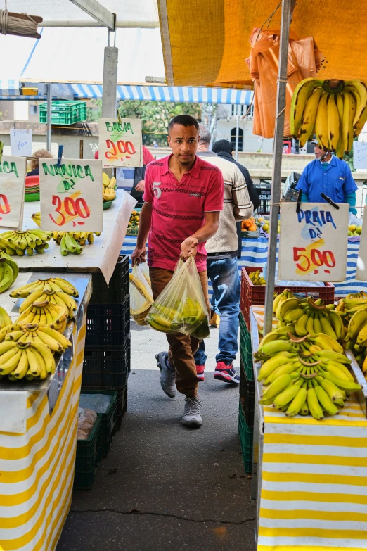 a vendor is carrying a bag of bananas at an outdoor market