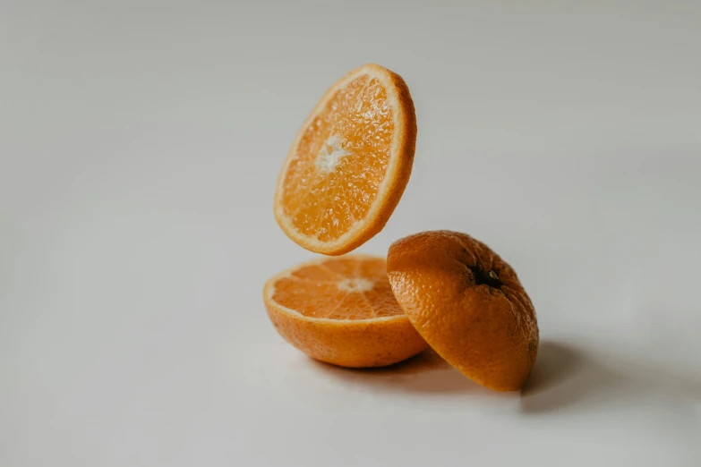 an orange on a table sliced in half with an end being taken out