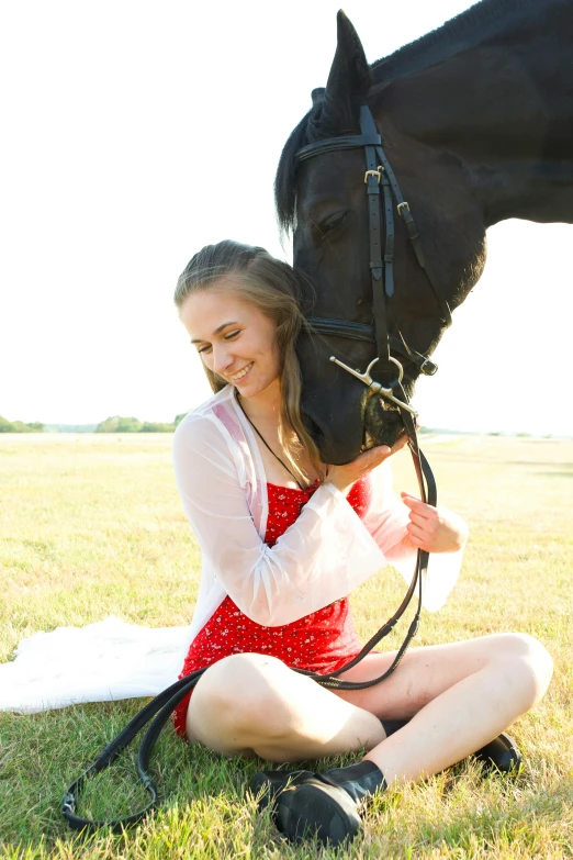 a young woman petting her black horse