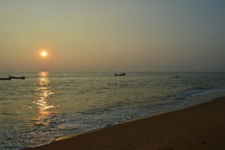 two small boats floating in the ocean under a setting sun