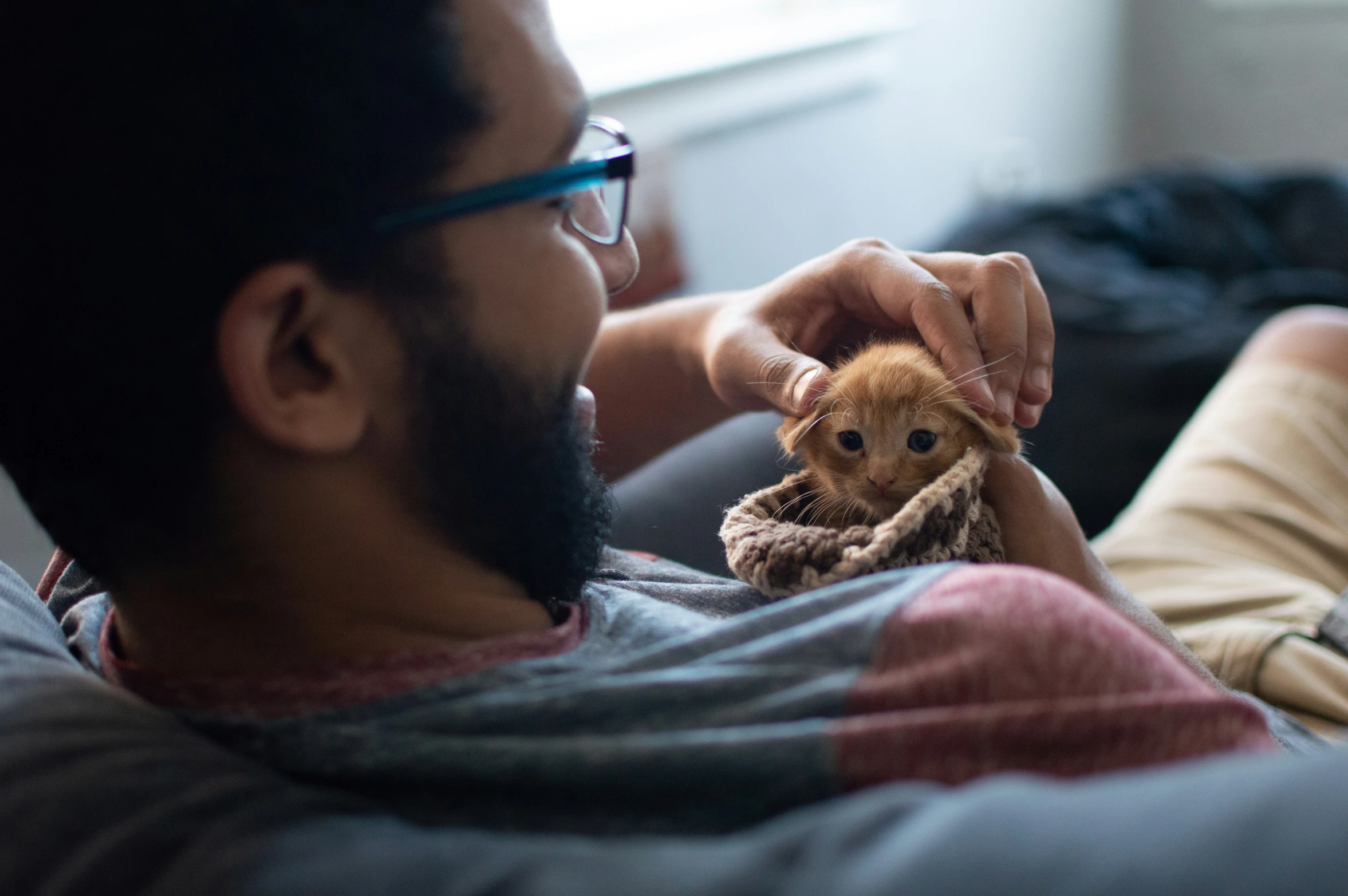 a man sits with a small teddy bear in his hands