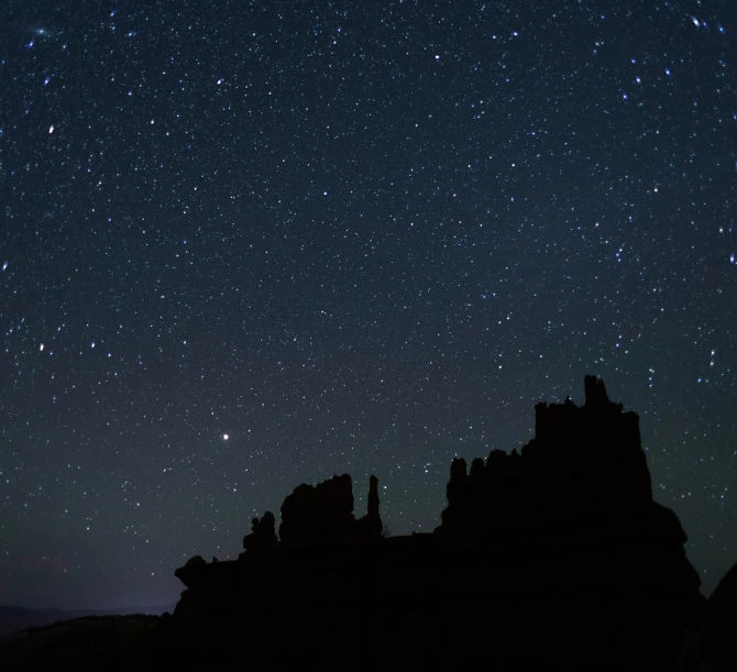 the sky is lit up with stars over rocks