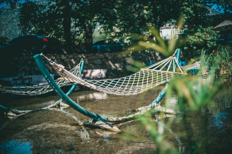 a blue hammock in the middle of water next to trees