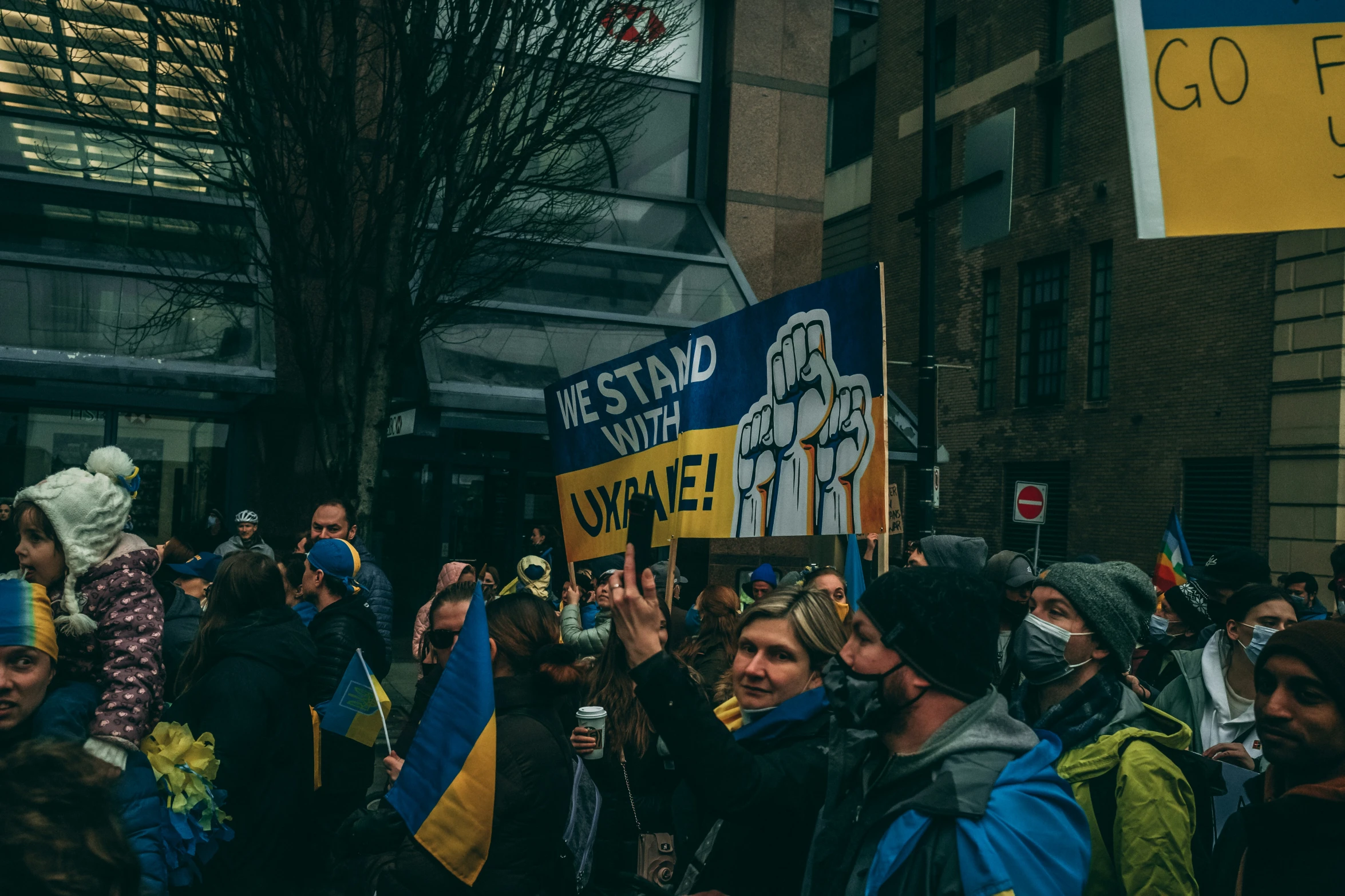 a group of people stand outside holding signs and flags