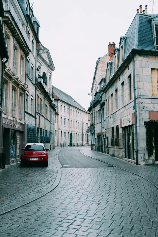 a red car sits in the middle of an empty street