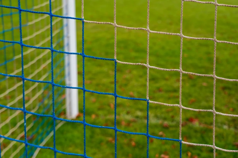 the closeup view of a net and a soccer ball in the background