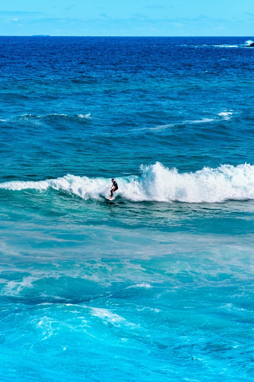 a person riding on the wave while the surfer stands on their board