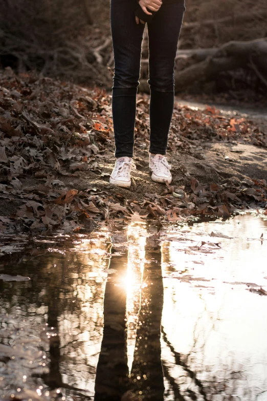 the person is wearing white sneakers by some leaves