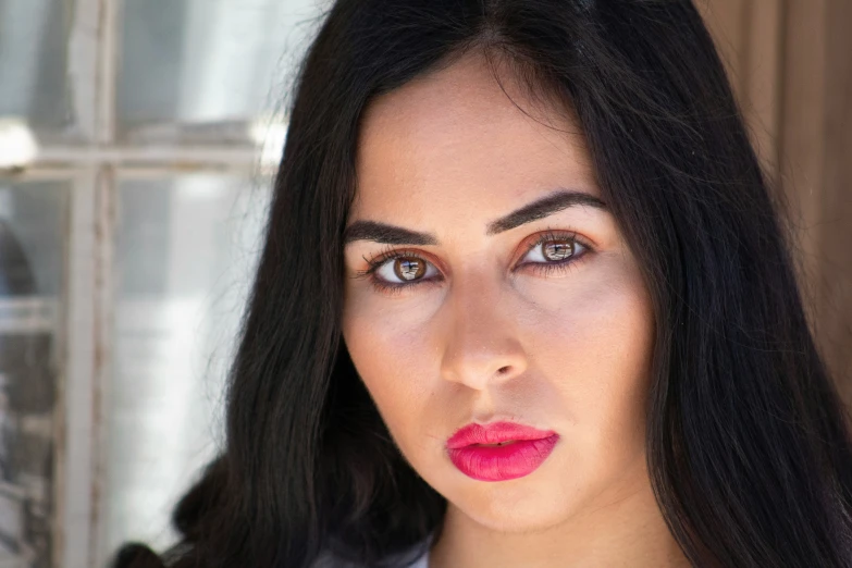 a woman with long dark hair and a pink lipstick