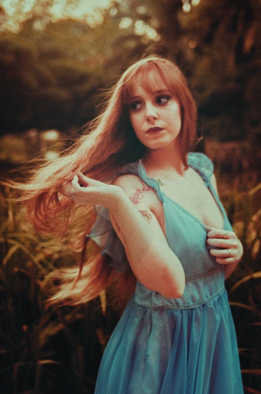 a woman with long red hair standing near tall grass