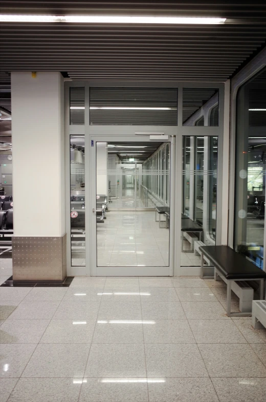 a hallway that has some benches next to a glass door