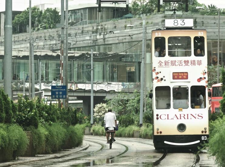 a passenger bus driving down the road next to a man on a bike