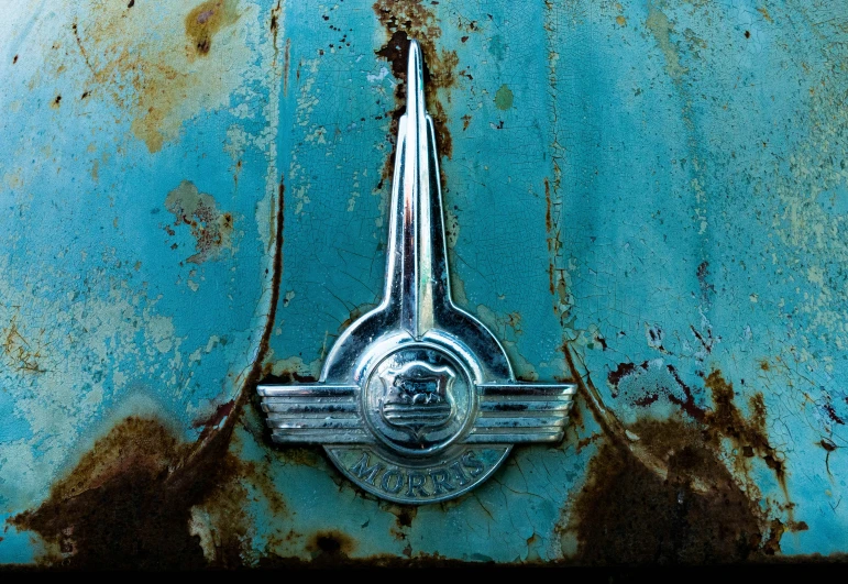 an antique metal emblem is shown on an old blue car