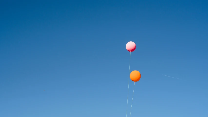 there are three balloons flying through the blue sky