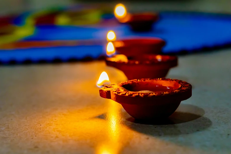 three small red pottery cups lit with brightly lit candles