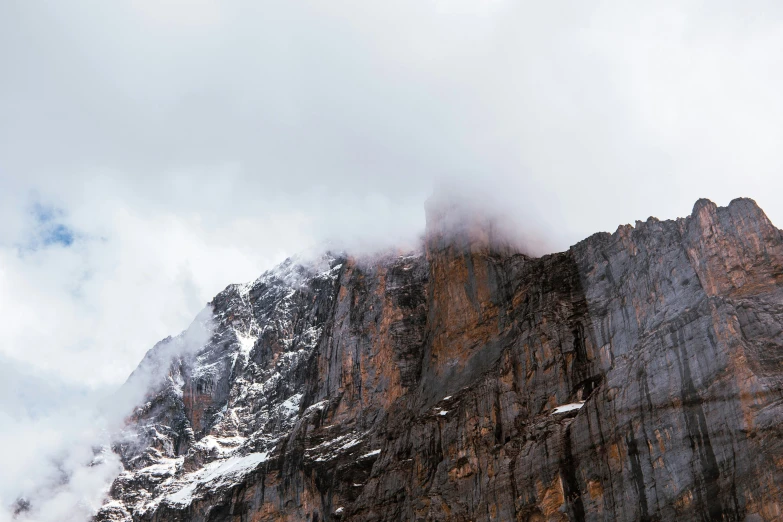 some clouds are rolling over a mountain and it's very steep