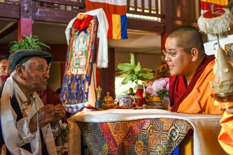 buddhist men wearing gold and white clothes in front of a table with flags