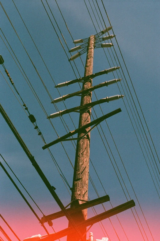 a phone pole in the sky is under a large electric pole