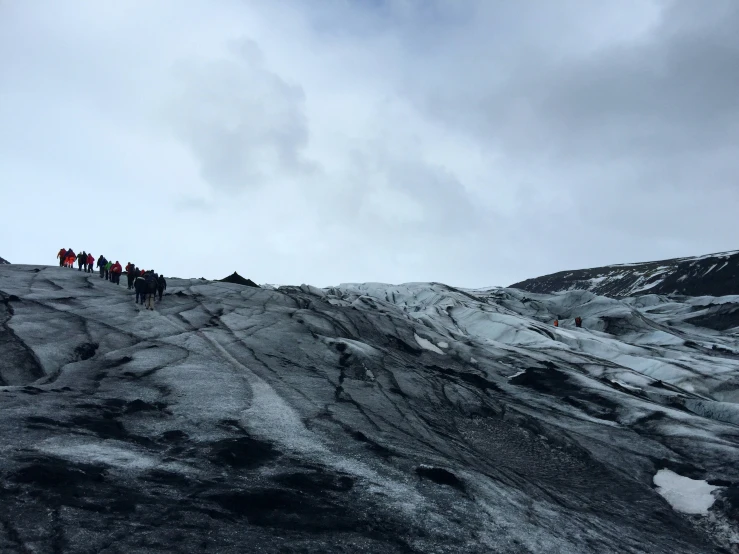 several people standing on a mountain side looking at the sky